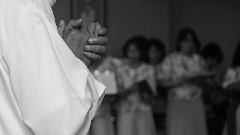 Pastor sangat khusyuk berdoa sambil mengepalkan jarinya di tengah ramainya penolakan di luar gedung, Jumat, 16 April 2025. (Foto: Fauzan Rafles/BandungBergerak.id)