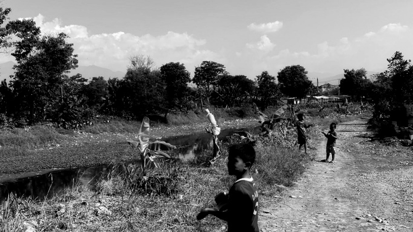 Anak-anak memainkan layangan di pinggir Sungai Citarum, Cicukang, Margaasih, Kabupaten Bandung, 26 Agustus 2025. (Foto: Ida Rosida/BandungBergerak)