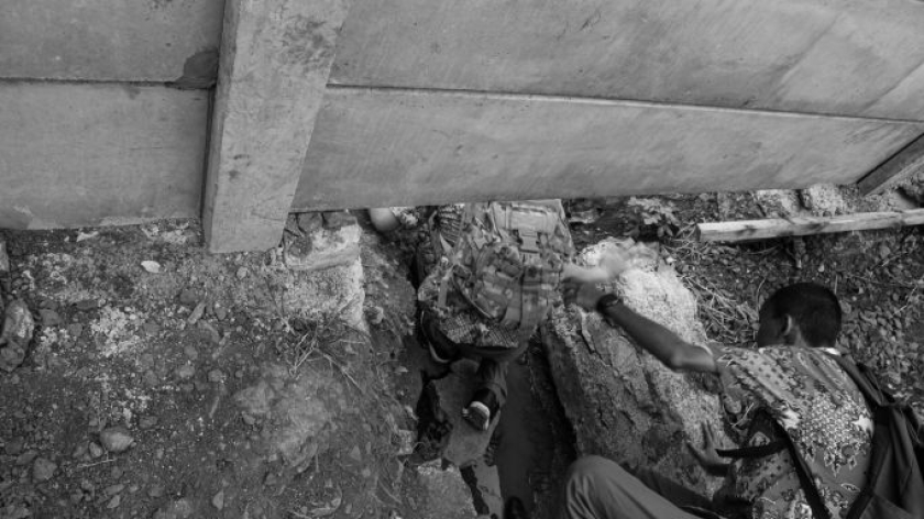 Orang menyeberang perlintasan sebidang di gorong-gorong Flyover Nurtanio, Bandung, 1 Januari 2025. Belum ada akses penyeberangan orang di kawasan ini. (Foto: Insan Radhiyan/BandungBergerak)