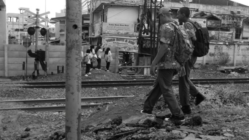Orang menyeberang perlintasan sebidang di gorong-gorong Flyover Nurtanio, Bandung, 1 Januari 2025. Belum ada akses penyeberangan orang di kawasan ini. (Foto: Insan Radhiyan/BandungBergerak)