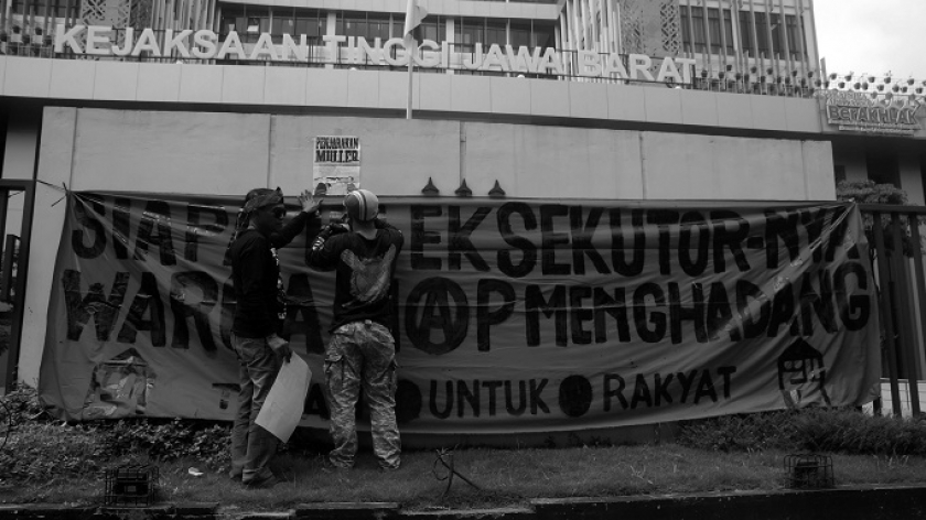 Warga Dago Elos menempelkan spanduk di pagar gedung Kejaksaan Tinggi Jawa Barat di Bandung, 13 Juni 2024. (Foto: Prima Mulia/BandungBergerak)