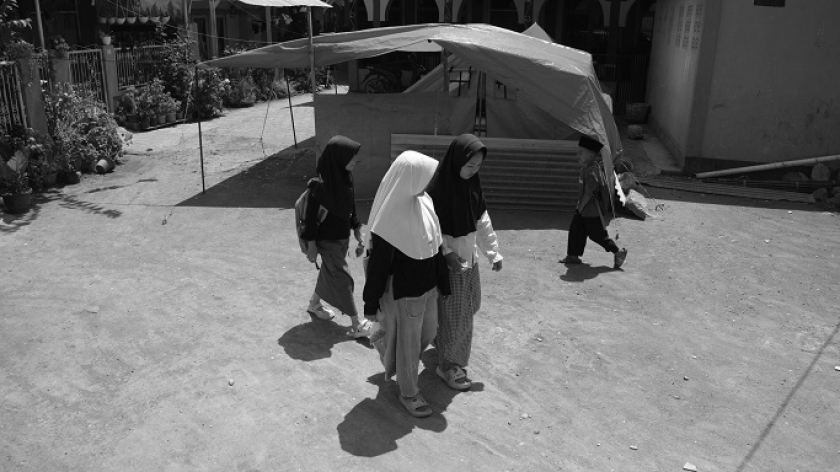 Santri madrasah ibtidaiyah Nurul Falah berjalan melewati tenda pengungsi saat akan masuk sekolah untuk pertama kali pasca gempa bumi magnitudo 4.9 di Desa Cikembang, Kecamatan Kertasari, Kabupaten Bandung, 30 September 2024. (Foto: Prima Mulia/BandungBergerak) 