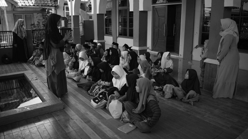Santri madrasah ibtidaiyah Nurul Falah menyimak penjelasan guru saat sekolah untuk pertama kali pascagempa di halaman masjid madrasah di Desa Cikembang, Kecamatan Kertasari, Kabupaten Bandung, 30 September 2024.(Foto: Prima Mulia/BandungBergerak) 