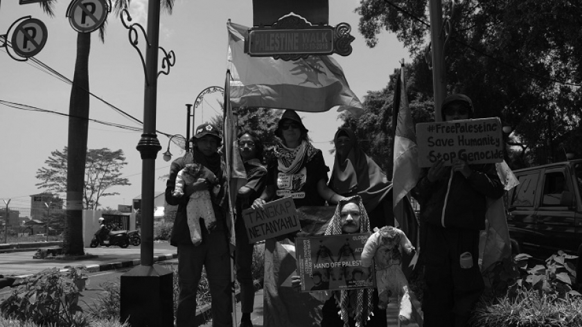 Aktivis dan seniman mengibarkan bendera Palestina mengacungkan poster di monumen Asia Afrika, Bandung, 7 Oktober 2024. (Foto: Prima Mulia/BandungBergerak)