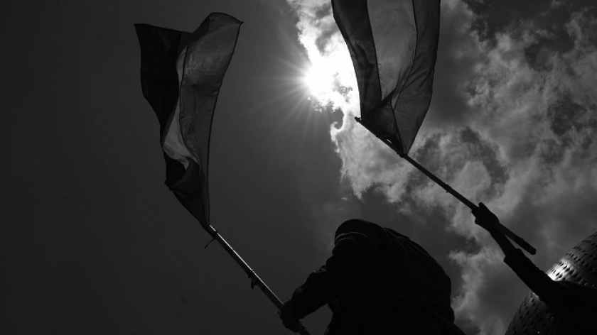 Aktivis dan seniman mengibarkan bendera Palestina mengacungkan poster di monumen Asia Afrika, Bandung, 7 Oktober 2024. (Foto: Prima Mulia/BandungBergerak)