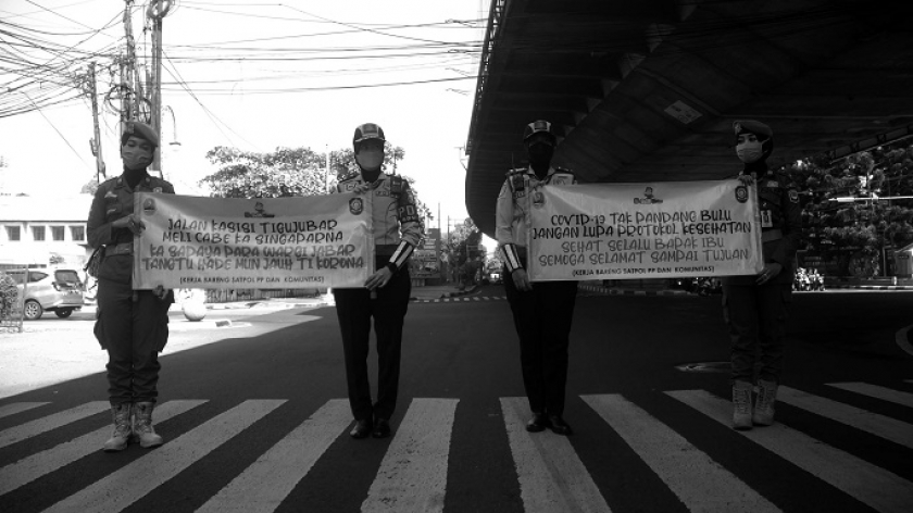 Petugas membentang poster kampanye 5M di simpang Cikapayang, Bandung,  30 Juli 2021. (Foto: Prima Mulia) 