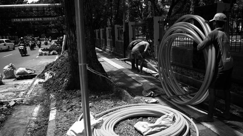 Proses pekerja memasukan pipa-pipa plastik ke dalam tanah di galian proyek ducting kabel serat optik Bandung bebas kabel udara di sejumlah ruas jalan protokol di Bandung, 10 Desember 2024. (Foto: Prima Mulia/BandungBergerak)