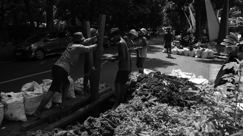 Proses pekerja memasukan pipa-pipa plastik ke dalam tanah di galian proyek ducting kabel serat optik Bandung bebas kabel udara di sejumlah ruas jalan protokol di Bandung, 10 Desember 2024. (Foto: Prima Mulia/BandungBergerak)