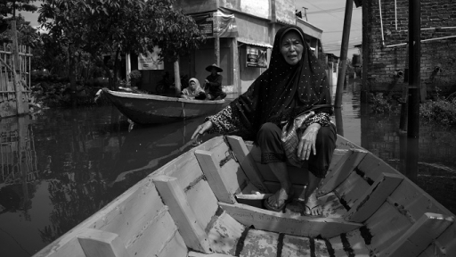 Tina (82) naik perahu menembus banjir luapan Sungai Citarum saat beraktivitas di Desa Cijagra, Kecamatan Bojongsoang, Kabupaten Bandung, yang sudah terendam banjir, 29 November 2024. (Foto: Prima Mulia/BandungBergerak)