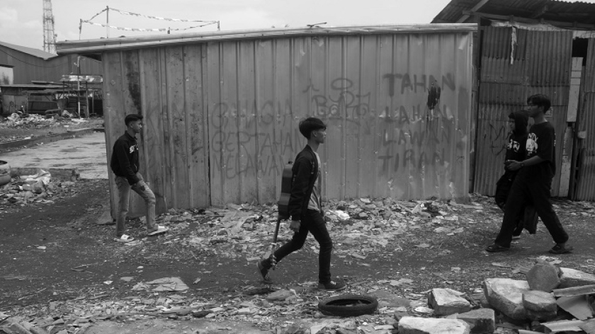 Warga berjalan melewati rumah yang bertahan di area konflik agraria Kampung Sukahaji,  Kecamatan Babakan Ciparay, Bandung, 17 Juni 2025. (Foto: Prima Mulia/BandungBergerak)