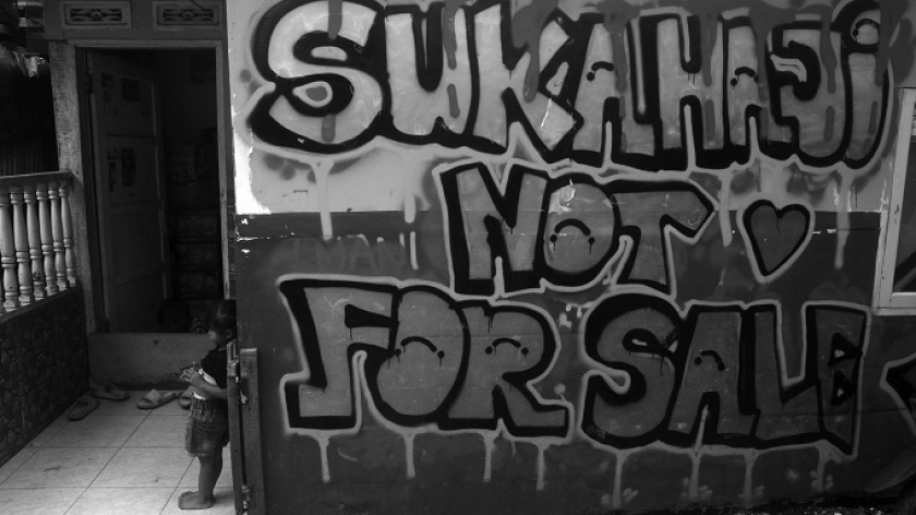 Grafiti di dinding rumah warga yang bertahan di area konflik agraria Kampung Sukahaji, 17 Juni 2025. (Foto: Prima Mulia/BandungBergerak)