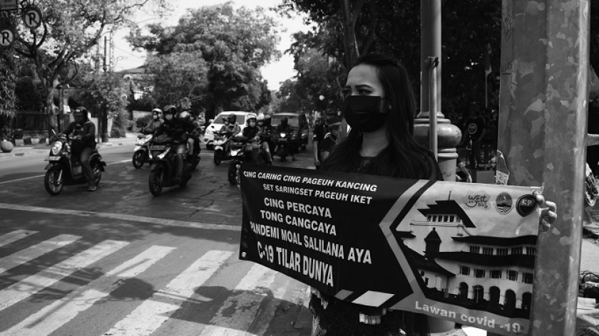 Pegawai Disparbud Jabar menggelar kampanye protokol kesehatan di lampu merah Jalan Martadinata, Bandung, Selasa (24/8/2021). Kampanye digalakkan setelah level PPKM wilayah Bandung Raya turun ke level 3. (Foto: Prima Mulia/BandungBergerak.id)