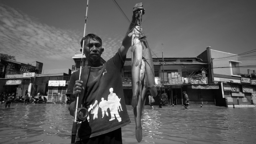 Warga menunjukkan hasil pancingan di jalan yang terendam banjir Bandung Selatan, Jawa Barat, 5 Desember 2025. (Foto: Prima Mulia/BandungBergerak)