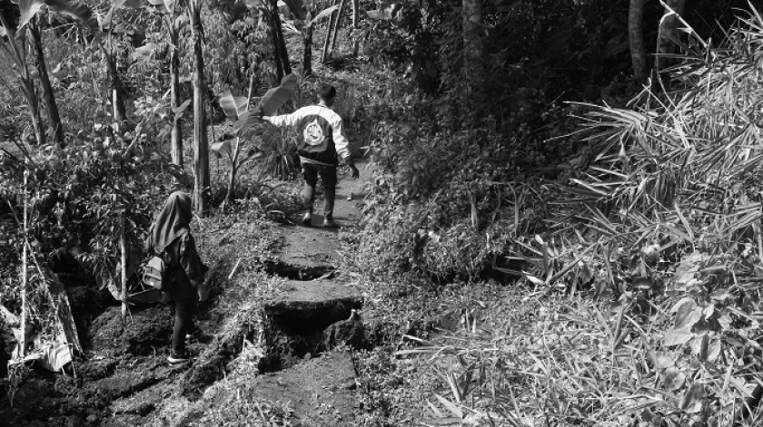 Pejalan kaki melintasi jalan alternatif yang terputus di Nanggerang, Cililin, 5 Desember 2025. (Foto: Insan Radhiyan/BandungBergerak)