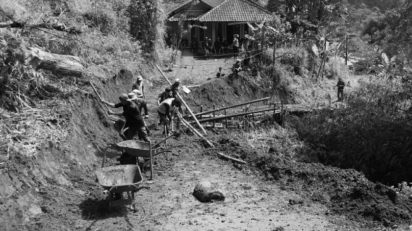 Petugas memperluas jalan dan menambal jalan dengan bambu beserta tanah merah di jalan yang terputus di area  penghubung Desa Ciririp dan Desa Bangsaya, 5 Desember 2025. (Foto: Insan Radhiyan/BandungBergerak)