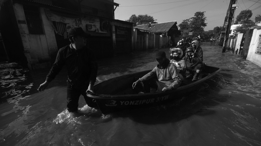 Warga menembus Jalan Raya Bojongsoang yang terencam banjir dengan perahu, 5 Desember 2025. (Foto: Prima Mulia/BandungBergerak)