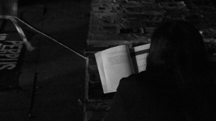 Seorang perempuan membaca buku yang disediakan Perjal Banjaran dengan cahaya remang-remang Alun-Alun Banjaran, Bandung, Sabtu 24 Januari 2026. (Foto: Maisan Rachman/BandungBergerak)