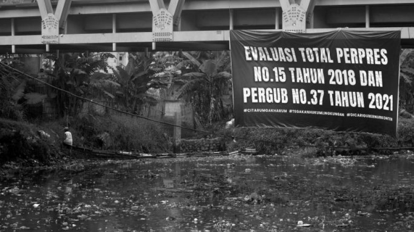 Aktivis memasang poster di atas hamparan sampah yang menutupi permukaan Sungai Citarum di Oxbow Bojongsoang, Kabupaten Bandung, 22 Mei 2026. (Foto: Prima Mulia/BandungBergerak)