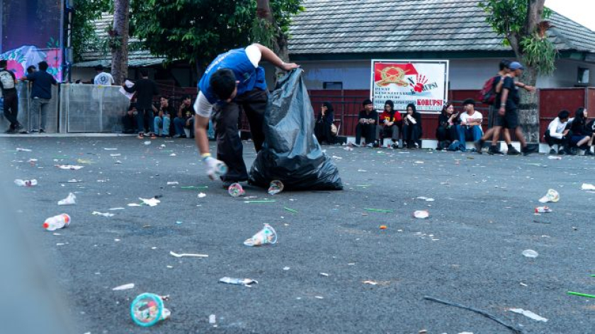 Petugas memungut sampah yang berserakan di Flower City Fest, Bandung, Minggu, 9 Agustus 2026. (Foto: Insan Radhiyan/BandungBergerak)