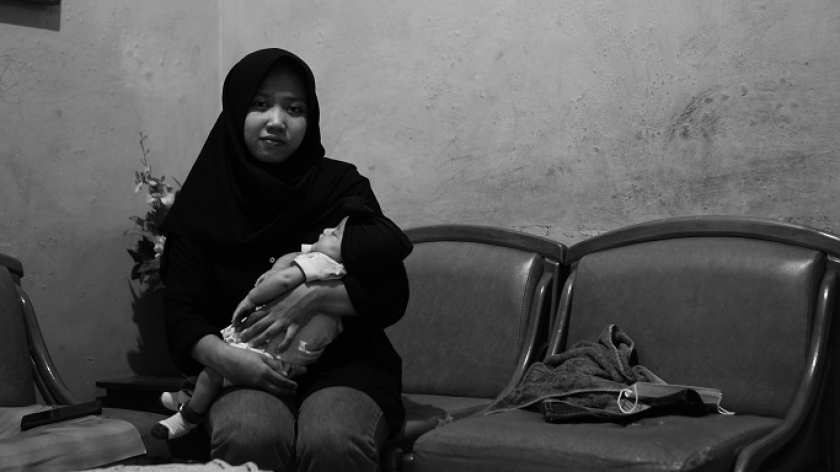 Rizka (23) sedang menggendong Aqila  di rumah kontrakannya di bilangan RW 004 Suka Asih, Bojongloa Kaler, Kota Bandung, Sabtu (28/8/2021). Ketika mengandung dan melahirkan anak pertamanyha itu, Rizka dan sang suami sedang berada dalam kondisi ekonomi terburuk terdampak pandemi. (Foto: Bani Hakiki/BandungBergerak.id)