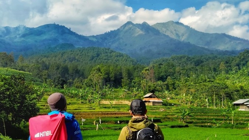 Dua pendaki menikmati pemandangan Gunung Sangar (tampak paling kiri) dari Kampung Pasirbentang, Desa Mekarjaya, Kecamatan Arjasari. Kabupaten Bandung, Agustus 2021. (Foto: Gan Gan Jatnika)