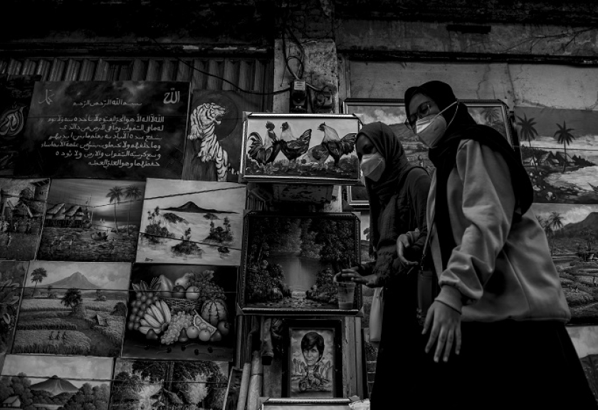 Dua orang perempuan mengenakan masker protokol kesehatan Covid-19 melintas di depan lukisan pinggir Jalan Braga, Bandung. (Foto:  Iqbal Kusumadirezza)