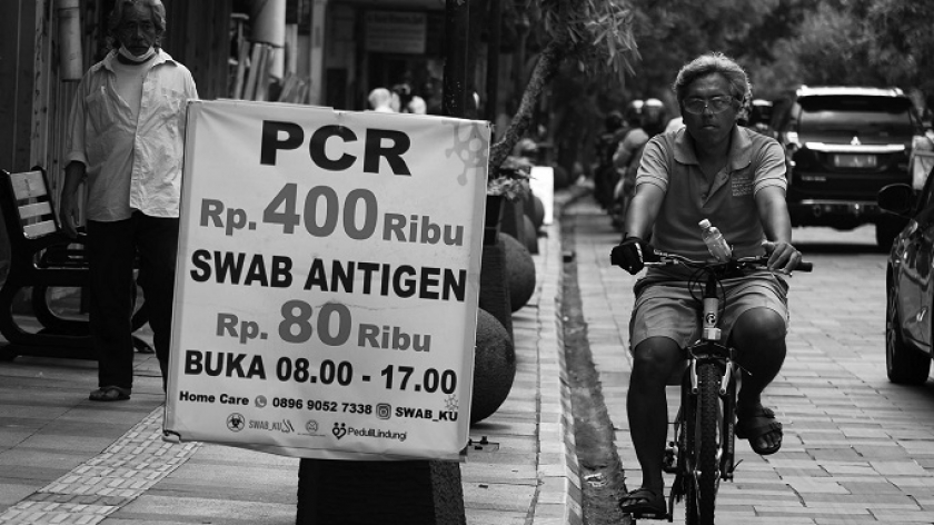 Poster promosi swab PCR di Jalan Braga, Bandung, Jawa Barat, Senin (1/11/2021). Pemerintah menetapkan batas harga tes PCR di Jawa Bali turun jadi Rp 275.000 atas desakan berbagai kalangan. (Foto: Prima Mulia/BandungBergerak.id)