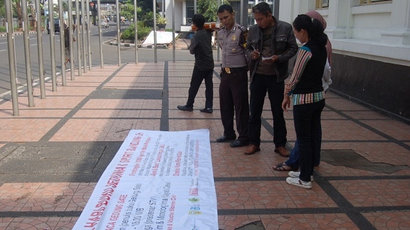 Dua polisi sedang menuliskan isi spanduk yang akan diikat di tiang bendera dan dibentangkan menghadap Jalan Asia Afrika, ditemani oleh Yostiani Noor Asmi dan Noel Sagalana selaku panitia (Foto tanggal: 25/4/2010. Sumber foto: Pubdok HBS 2010).