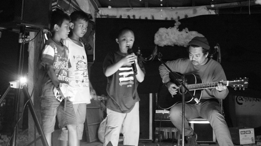 Aye (8) dengan berani maju ke panggung dan bernyanyi di hadapan teman-temannya dalam puncak rangkaian pantas seni di Anyer Dalam, Kota Bandung, Minggu (30/1/2022). Aye merupakan satu dari puluhan anak korban penggusuran. (Foto: Emi La Palau/BandungBergerak.id)