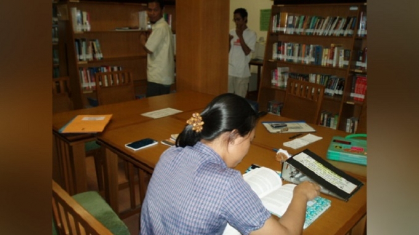 Ruangan koleksi dan meja baca Balepustaka. Tampak di foto: Ratna (duduk membaca buku), Azmi, dan Didin (Foto tanggal: 29/11/2005. Sumber foto: Deni Rachman)