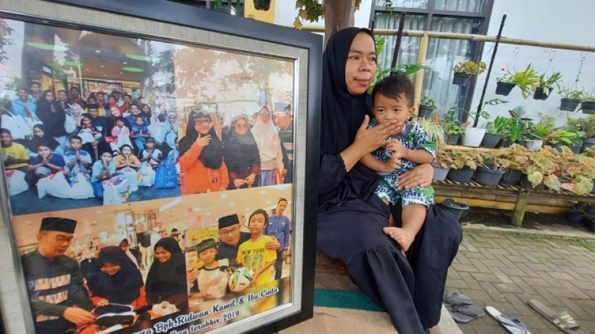 Imas sedang mengendong dan menunjukkan foto kenangan-kenangan bersama Ridwan Kamil dan Ibu Cinta. Imas adalah Pengasuh Panti Yatim dan Dhuafa Roudotul Amanah, Kabupaten Bandung Barat. (Foto: Bagus Fallensky)