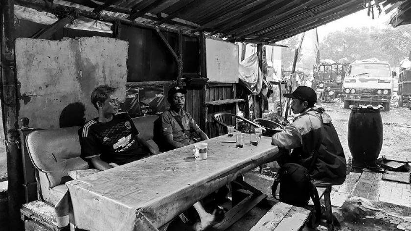 Dendi (34), buruh bongkar muat sampah, berbincang dengan rekannya di warung sekitar TPS Gedebage, Kota Bandung, Sabtu (14/1/2023). (Foto: Awla Rajul/BandungBergerak.id)