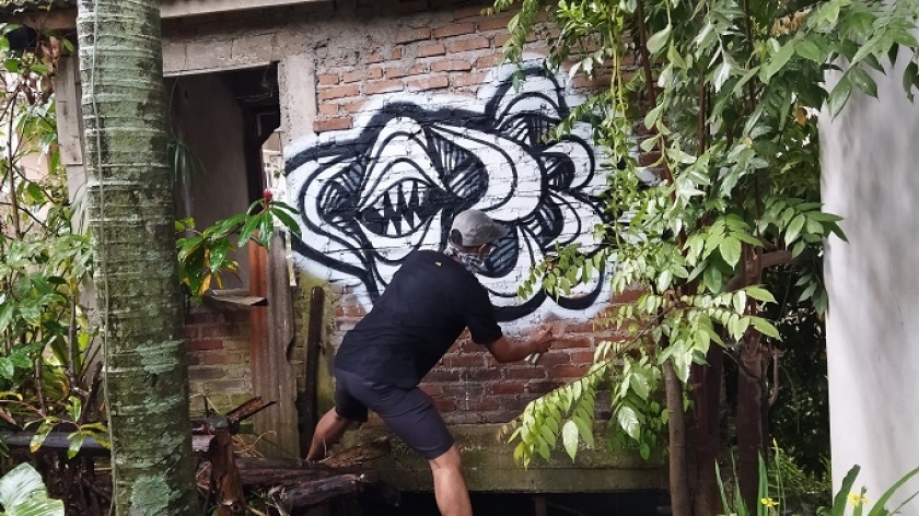 Seorang peserta melukis mural di dinding rumah warga dalam acara Dialog antara Kita: Melukis dan Menulis di Nugenah, yang diadakan di Nugenah Kopi, di Cicalengka, Kabupaten Bandung. (Foto: Hafidz Azhar)