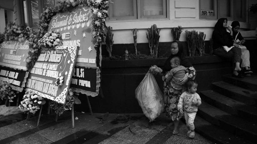 Warga melintas di depan deretan karangan bunga berisi ucapan selamat di pembukaan Rakornas Partai Hanura di kompleks Gedung Merdeka Bandung, Kamis (2/3/2023). (Foto: Prima Mulia/BandungBergerak.id)