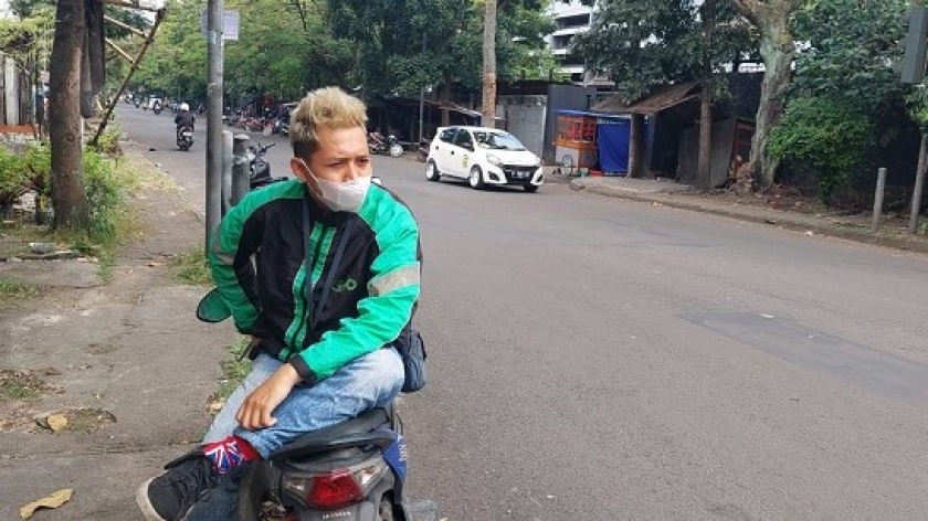 Reyhan Bahari (27), seorang sopir ojol, sedang menanti penumpang di Jalan Suryani, Kota Bandung. (Foto: Yogi Esa)