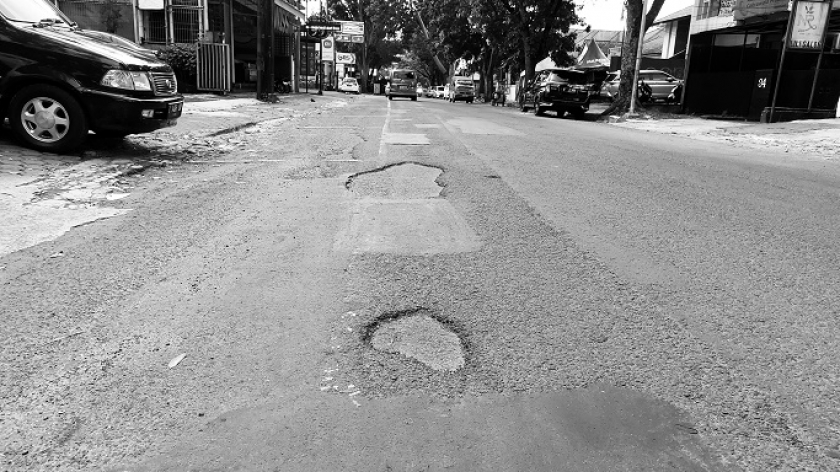 Aspal hasil tambalan mengelupas dan menghasilkan jalan berlubang di Kota Bandung. (Foto: Awla Rajul/BandungBergerak.id)