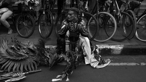 Peserta parade budaya melepas lelah di atas trotoar. , Sabtu (29/7/2023). (Foto: Prima Mulia/BandungBergerak.id)