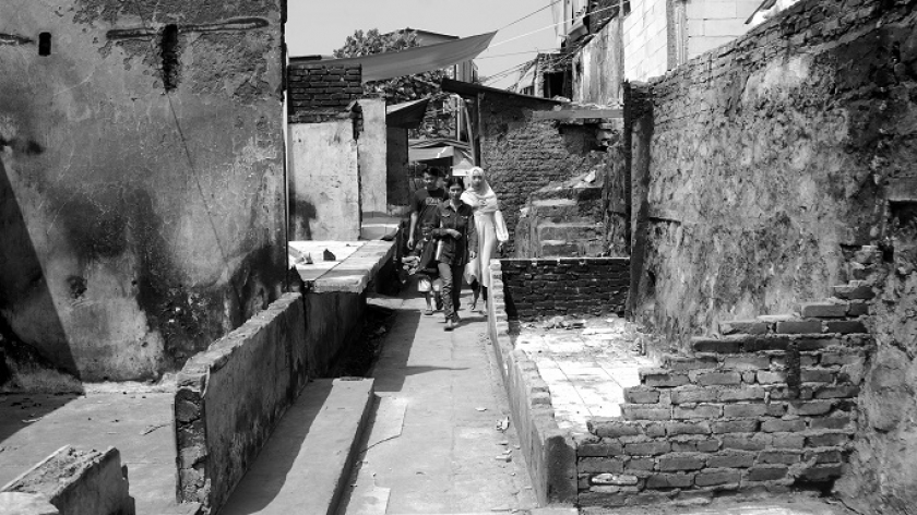 Warga melintas di antara dinding Pasar Sadang Serang yang hangus, Selasa (22/8/2023). (Foto: Prima Mulia/BandungBergerak.id)