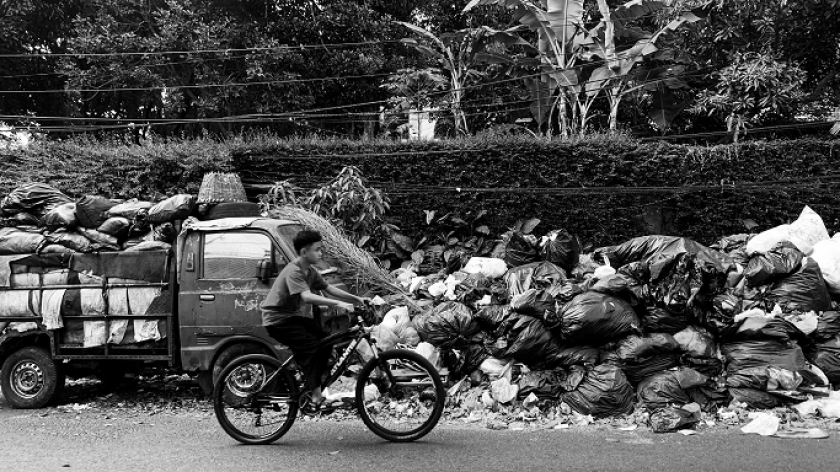 Warga melintas di depan tumpukan sampah di Jalan Bukit Jarian, Kelurahan Hegarmanah, Cidadap, Kota Bandung. Rabu, 27 September 2023. (Foto: Emi La Palau/BandungBergerak.id) 