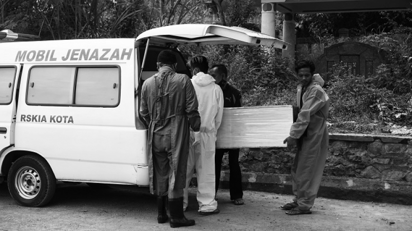 Acep Tegus dan tandemnya, Irfan, berinisiatif membantu mengangkut jenazah dari ambulans ke liang lahat karena keterbatasan jumlah pemangku jenazah di TPU Cikadut Bandung, Jumat (25/6/2021). (Foto: Bani Hakiki)