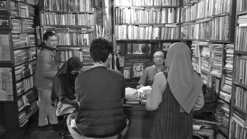 Anton Solihin (berkacamata di balik meja) sedang melayani beberapa pengunjung di perpustakaan Batu Api, 1 November 2023 (Foto: Muhammad Andi Firmansyah)