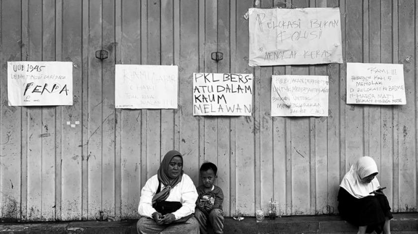 Yuni, 36 tahun, PKL Sosis dan Jam tangan di Dalem Kaum, bersama kedua anaknya, masih terus bertahan di lokasi. (Foto: Emi La Palau/BandungBergerak.id)