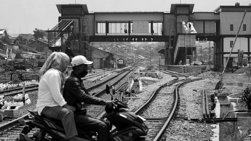 Kereta api berhenti di Stasiun Cicalengka lama, Kabupaten Bandung, dengan latar depan skybridge bangunan stasiun baru, Minggu, 7 Januari 2024. (Foto: Prima Mulia/BandungBergerak.id)