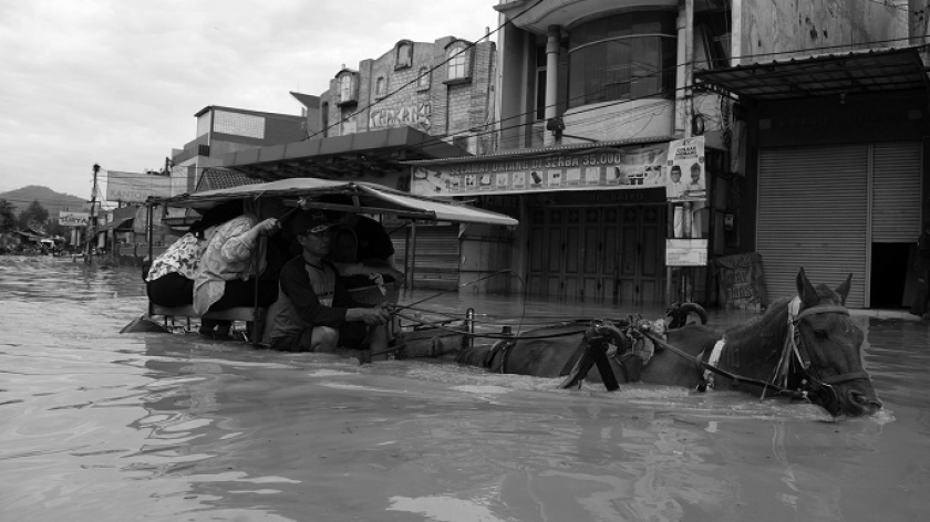 Warga naik delman lewat Jalan Raya Dayeuhkolot,  Kabupaten Bandung, dilanda banjir, 12 Januari 2024. (Foto: Prima Mulia/BandungBergerak.id) 