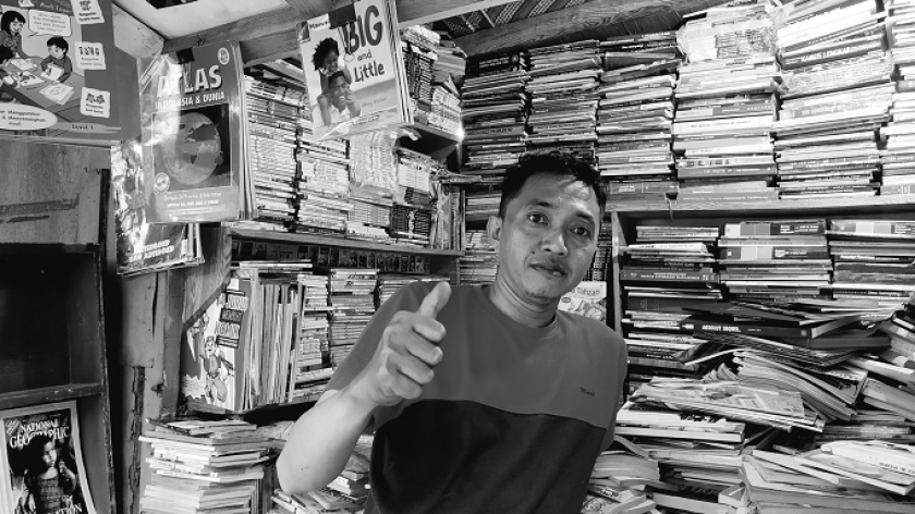 Dian (38 tahun) berpose di depan kios buku di Jalan Dewi Sartika, Kamis, 7 Desember 2023. (Foto: Muhammad Akmal Firmansyah/BandungBergerak.id)