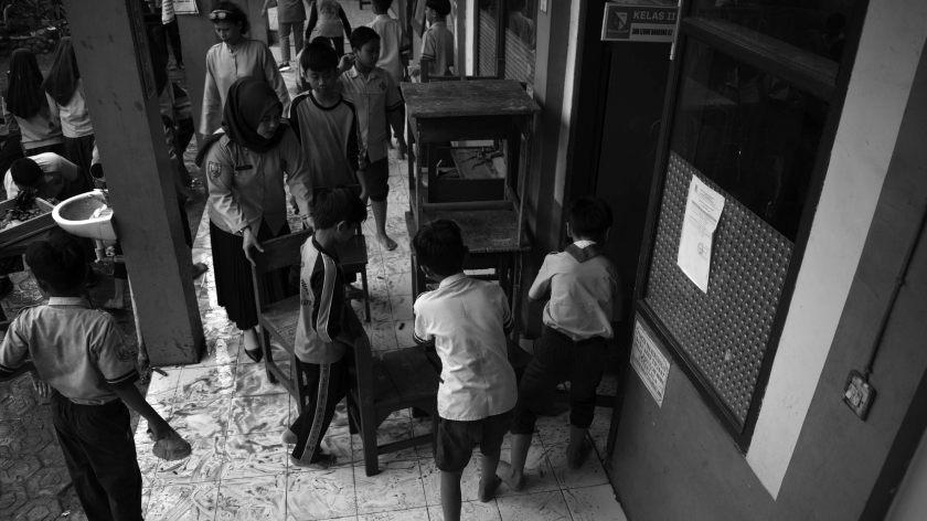 Murid SDN Leuwibandung 3 membawa  meja kursi bersih ke kelas pascabanjir besar di Desa Citeureup, Kecamatan Dayeuhkolot, Kabupaten Bandung, 15 Januari 2024. (Foto: Prima Mulia/BandungBergerak.id) 