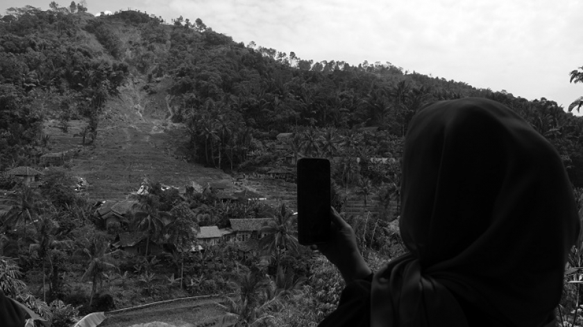 Warga Kampung Gintung, Desa Cibenda, Kecamatan Cipongkor, Kabupaten Bandung Barat, memotret longsoran bukit yang menghantam permukiman di bawahnya, 25 Maret 2024. (Foto: Prima Mulia/BandungBergerak.id)