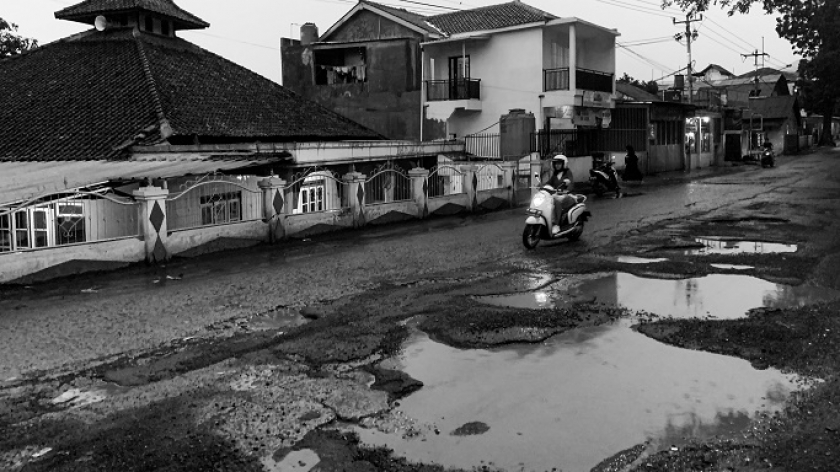 Kendaraan memilih mengambil jalur yang berlawanan untuk menghindari lubang tergenang air di Cicalengka, Kabupaten Bandung, Rabu, 6 Maret 2024. (Foto: Ryamizar Hutasuhut/BandungBergerak.id)