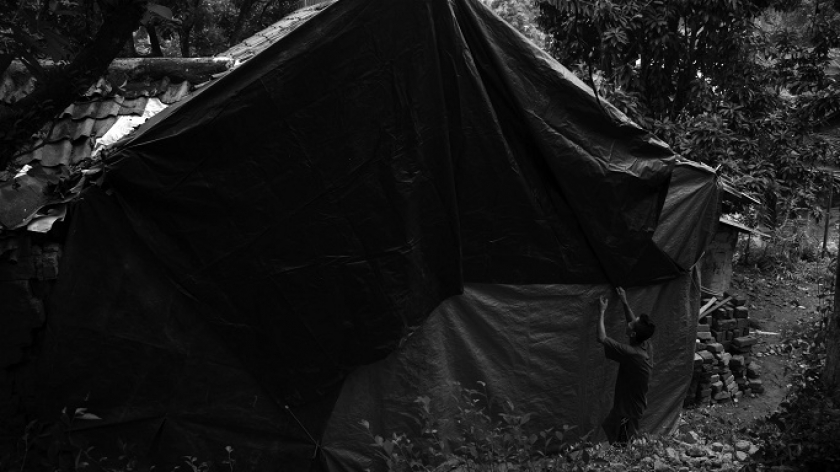 Engkos (52) mengencangkan terpal penutup dinding rumahnya yang jebol terdampak gempa Garut di Kampung Citatah, Kecamatan Cipatat, Kabupaten Bandung Barat, 28 April 2024. (Foto: Prima Mulia/BandungBergerak.id)